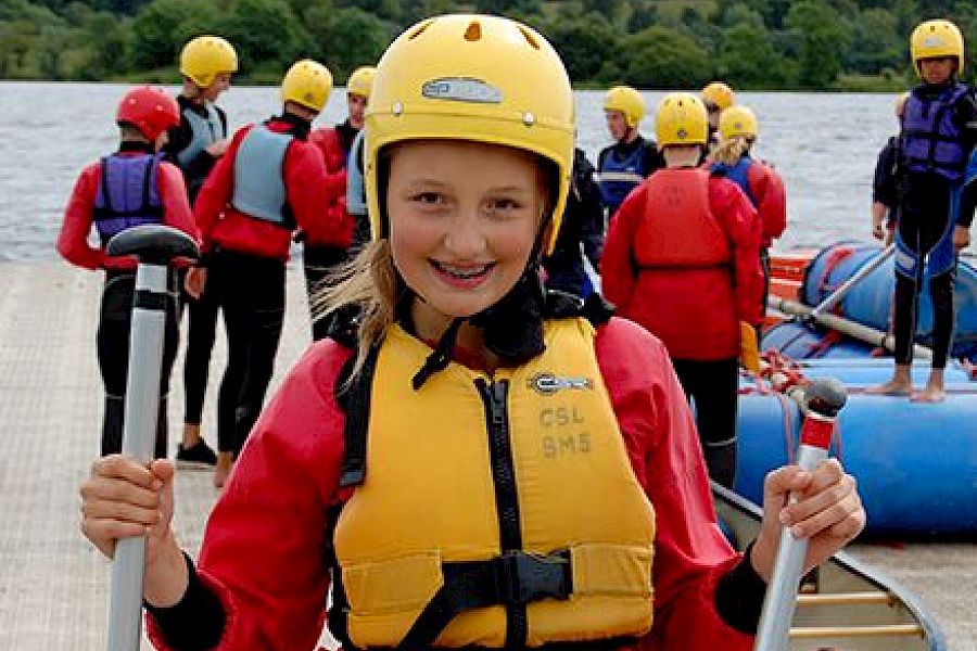 ISSFT student wearing a lifejacket and helmet, holding kayak equipment