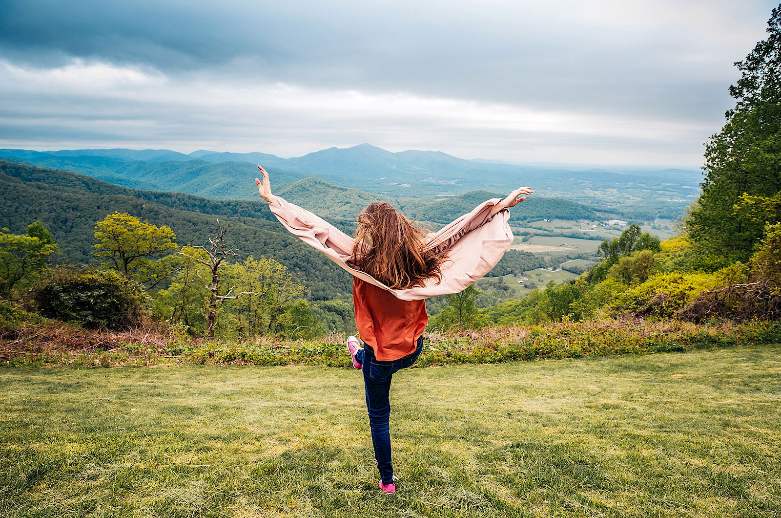 Teenage girl on top of a hill with her hands in the air