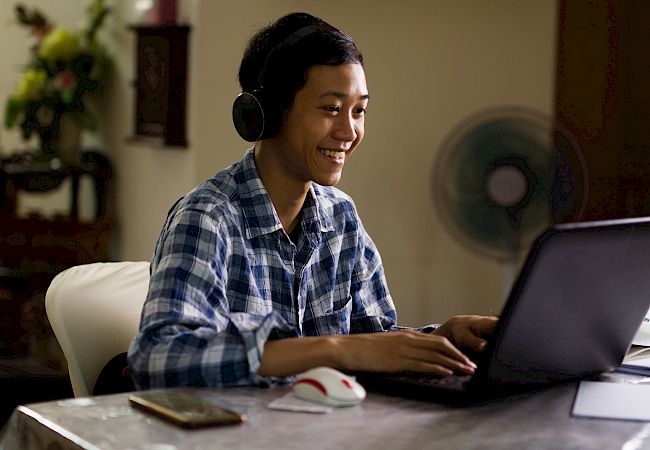 Young male smiling while using laptop