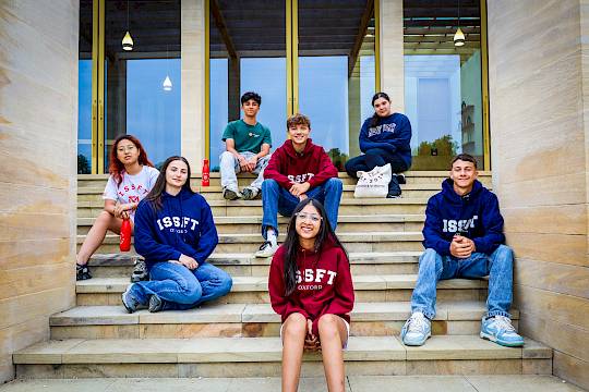 International summer school students sitting on steps of Worcester College, University of Oxford, during ISSFT’s 2025 programme