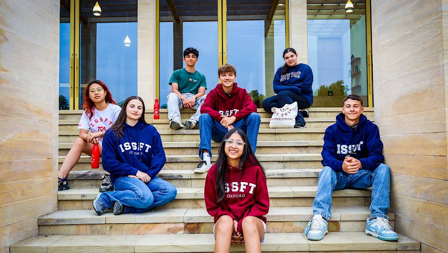 International summer school students sitting on steps of Worcester College, University of Oxford, during ISSFT’s 2025 programme